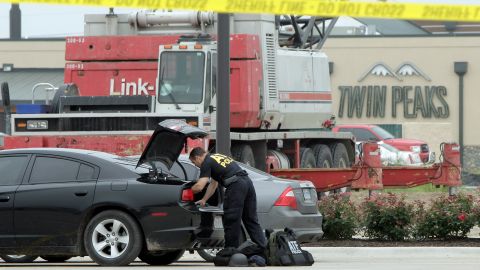 La Policía en Waco, Texas, recoje evidencias de veh'iculos estacionados en el restaurante donde se enfrentaron dos pandillas de moticiclistas el domingo pasado.