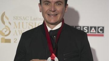 El cantante colombiano Fernando Fonseca presume presea en la alfombra roja de los premios SESAC Latina.