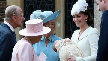 La Reina Isabel, en rosa, mira a la recién bautizada Charlotte, en brazos de su madre, Kate Middleton.