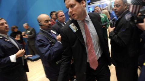 Varios corredores de la bolsa observan sorprendidos.