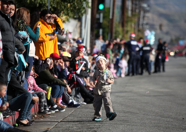 Un niño improvisa su propio desfile mientras cientos esperan en las cunetas del bulevar.