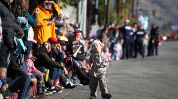 Un niño improvisa su propio desfile mientras cientos esperan en las cunetas del bulevar.