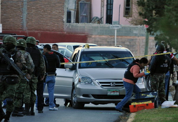 Peritos forenses investigan junto al vehículo donde el comandante de la Policía Municipal de Saltillo, capital del estado norteño de Coahuila (México), y su hijo de 11, años fueron asesinados por  sicarios.