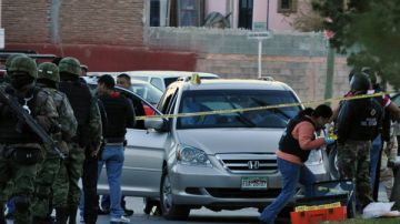 Peritos forenses investigan junto al vehículo donde el comandante de la Policía Municipal de Saltillo, capital del estado norteño de Coahuila (México), y su hijo de 11, años fueron asesinados por  sicarios.