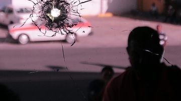 Vista de una puerta de vidrio del diario La Tribuna donde impactaron unos disparos tras un atentado contra ese medio de comunicación.