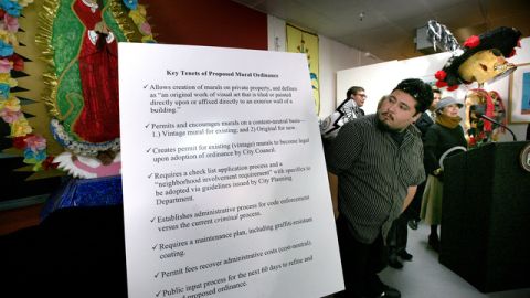 El artista Raúl González junto a un cartel con los puntos más importantes de la ordenanza.