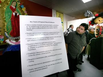 El artista Raúl González junto a un cartel con los puntos más importantes de la ordenanza.