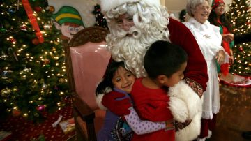 Los hermanitos Benites, Neyra y  René, abrazan a Santa Claus luego que este les diera su regalo navideño.