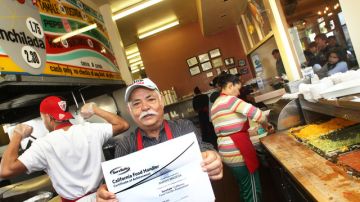 Amador Madera,  experimentado cocinero de Tito's Tacos, muestra con orgullo su certificado de Manejador de Comida.