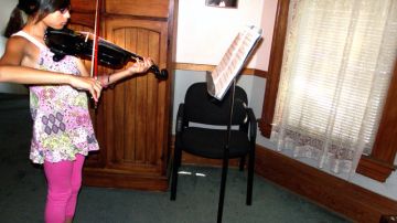 Vanessa Martínez, estudiante de la Neighborhood Music School, practica el violín.  La escuela fundada en 1914 ofrece sus clases  en una casa victoriana sobre la Avenida Boyle de Boyle Heights desde 1947.
