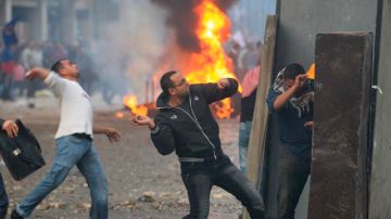 Manifestantes lanzan piedras a las fuerzas de seguridad de Egipto durante una protesta en El Cairo.