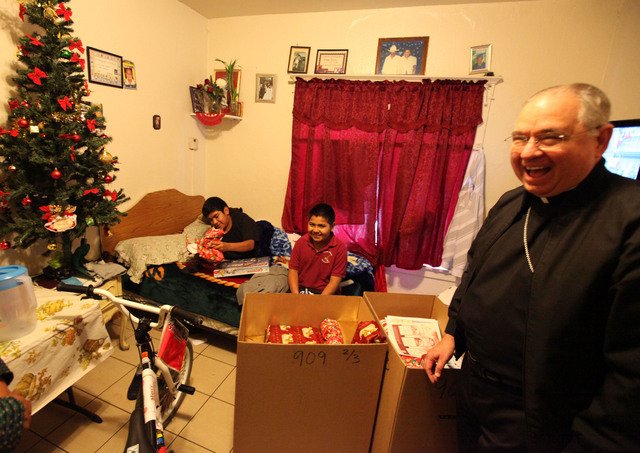 El Arzobispo Gómez sonríe tras sorprender con regalos a los hermanos Sixtos (izq.) y Alejandro García en su hogar cerca del centro de Los  Ángeles.