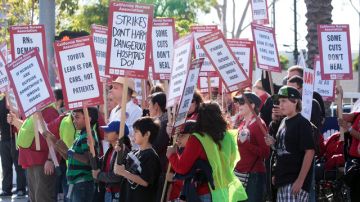 Docenas de personas cargan carteles como muestra de apoyo a los enfermeros en Long Beach.