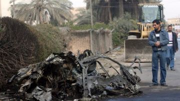 Un hombre contempla los restos de un coche bomba en el barrio de Yarmuck, en Bagdad, donde hubo varias explosiones.
