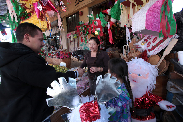 Entre coloridas piñatas y variados dulces, Armando Alvarado con su hija Valeria  se preparan para la Nochebuena.