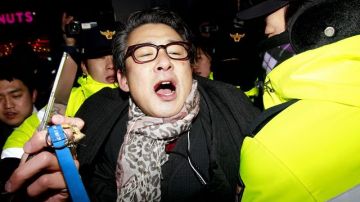 Efectivos policiales de Corea del Sur detienen a un manifestante que pensaba rendir homenaje al líder norcoreano Kim Jong-il, en Seúl.