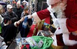 Un hombre disfrazado como Papá Noel entrega regalos en un puesto de "intercambio de presentes" en el mercado postnavideño.