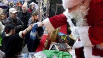 Un hombre disfrazado como Papá Noel entrega regalos en un puesto de "intercambio de presentes" en el mercado postnavideño.