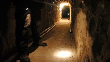 Un policía mexicano enciende  su linterna para mostrar el interior de este  túnel que tiene  3798 pies de largo,   que pasa de México a EE.UU. por el sur de California.