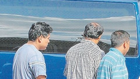 Trabajadores indocumentados suben a un vehículo oficial tras una redada.