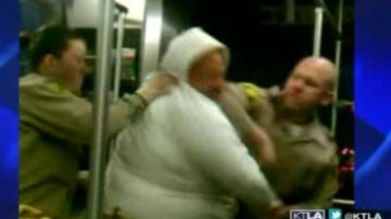 Una imagen del video, tomado de la televisión, muestra cuando uno de los agentes golpea con el codo a la mujer.