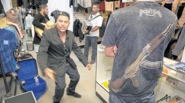 Un joven muestra la parte de atrás de una camiseta con una AK-47 mientras Raúl Becerra, de Clika Los Necios, canta en la tienda Antrax de Chula Vista.