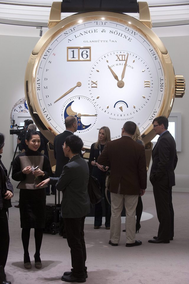 Periodistas conversan ante una maqueta de un reloj de la firma 'Lange and Soehne' en el Salón Internacional de la Alta Relojería de Ginebra.
