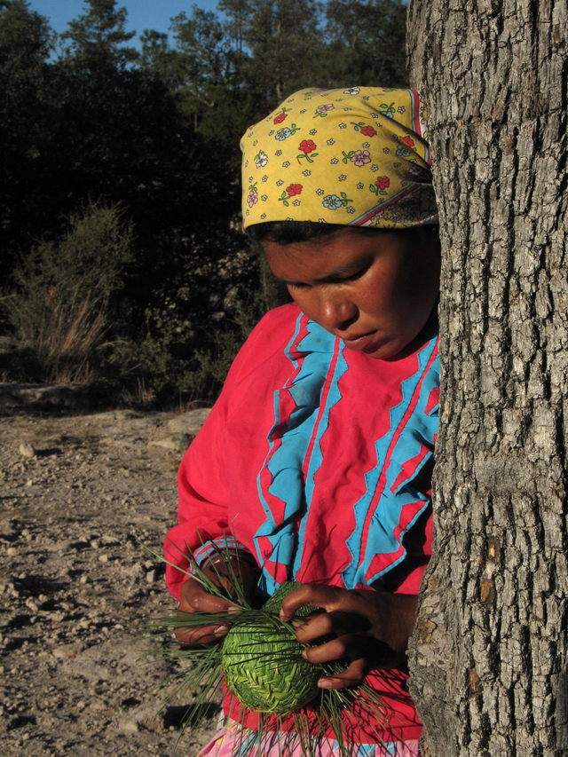Una joven tarahumara trabaja una manualidad.
