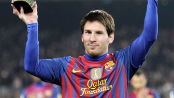 El argentino Lionel Messi, delantero del Barcelona, enseña su tercer balón de oro a la afición congregada en el Camp Nou, antes del partido del Barça ante el Betis.