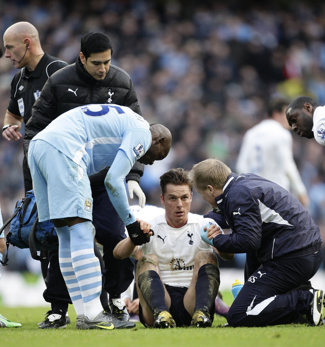 Mario Balotelli (izq.) de Manchester City intenta ayudar a Scott Parker, después de haberle pisado la cabeza en la jugada precedente.