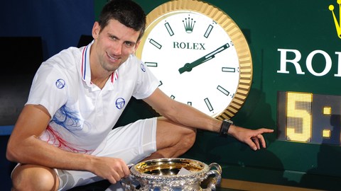 Presumiendo su trofeo, Novak Djokovic posa junto al reloj que marca 5:53: el tiempo que duró su juego.