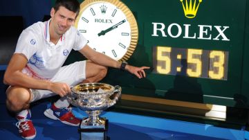 Presumiendo su trofeo, Novak Djokovic posa junto al reloj que marca 5:53: el tiempo que duró su juego.