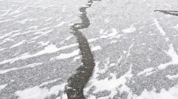 Un joven camina con precaución sobre un lago helado.