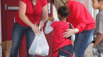 Oficiales de la escuela primaria Engelwood en Orlando, con un 79% de estudiantes hispanos,  entregan bolsas de comida a estudiantes.