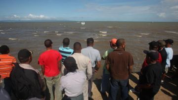 Varias personas observan el operativo de rescate al naufragio de una frágil embarcación ocurrido la madrugada del sábado pasado en las costas del noreste dominicano.