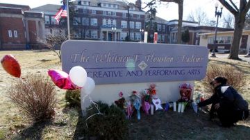 Joanna de la Rosa, de Montclair, Nueva Jersey, coloca flores a las afueras de la academia que lleva el nombre de Whitney Houston en este estado.