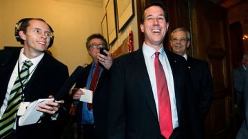 Rick Santorum sonríe mientras periodistas intentan obtener una declaración de su parte.