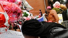 Yamda Johnson besa una foto de Whitney Houston al visitar hoy junto a su amiga Regina Kujemya la iglesia en Newark donde será el funeral.