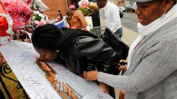 Yamda Johnson besa una foto de Whitney Houston al visitar hoy junto a su amiga Regina Kujemya la iglesia en Newark donde será el funeral.