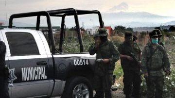 Oficiales investigan la escena del hallazgo de los cuerpos.