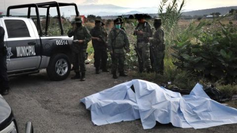 Oficiales investigan la escena del hallazgo de los cuerpos.