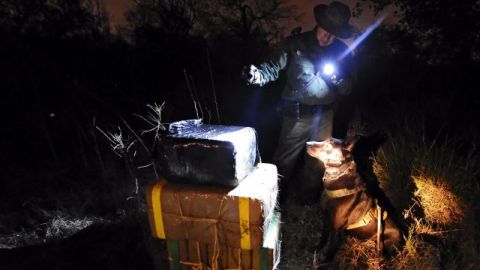 Un agente fronterizo vigila varios fardos de marihuana tras encontrarlos entre la maleza a orillas de Río Grande.