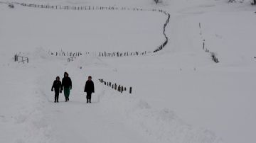 Personas caminan en la nieve.