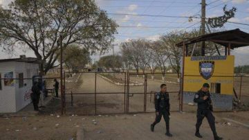 Policías hondureños caminan frente a la entrada de la Granja Penal de Comayagua en la que el martes murieron 356 presos por un incendio.