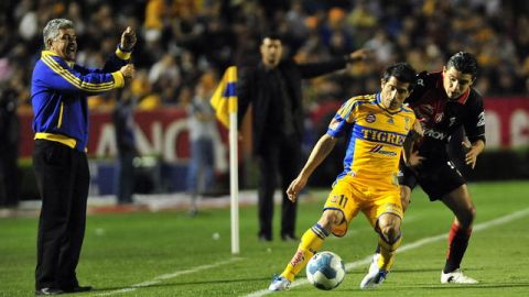 Ricardo Ferretti grita a sus pupilos, mientras Damián Álvarez protege el esférico ante la llegada de Jesús Paganoni, del Atlas, en acción del partido de ayer en la cancha del Estadio Universitario.