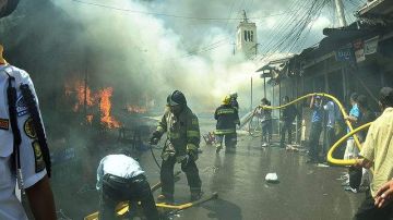 Bomberos exhaustos trabajaban para extinguir las llamas de un incendio que calificaron de enorme.
