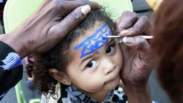 Una niña espera que le pinten la cara, una de las actividades para pequeños en el Mardi Gras de Farmers Market.