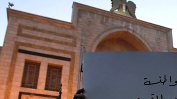 Un sirio muestra un cartel en el que se lee "Sí a la ciudadanía, no a la discriminación y al tercer artículo.