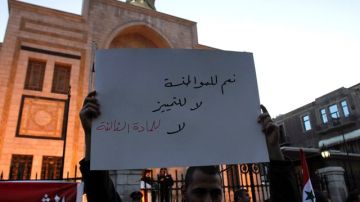 Un sirio muestra un cartel en el que se lee "Sí a la ciudadanía, no a la discriminación y al tercer artículo.