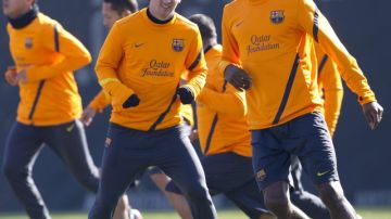 Leo Messi (izq.) y Eric Abidal (der.)  calientan durante la sesión de entrenamiento efectuada el jueves por el FC Barcelona en la ciudad deportiva Joan Gamper.